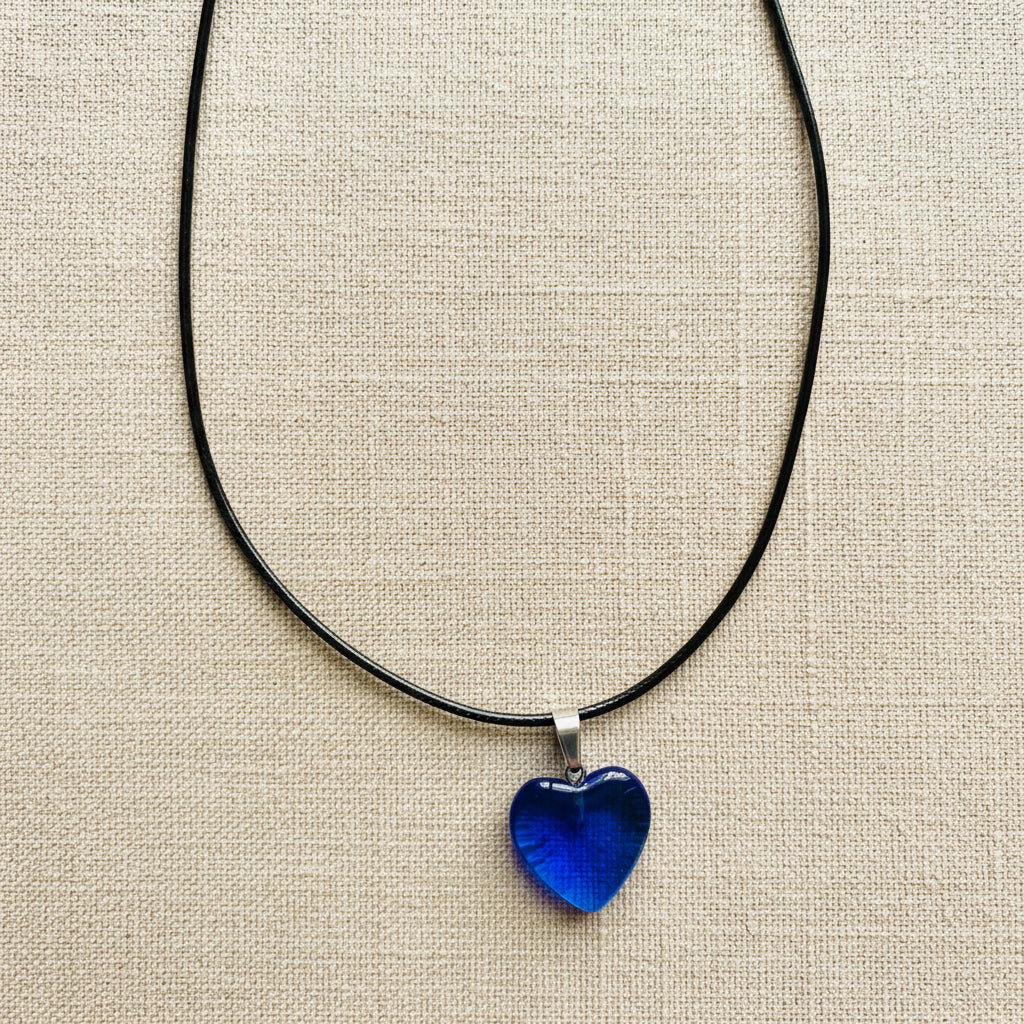 Blue heart-shaped pendant on a black cord against a neutral background