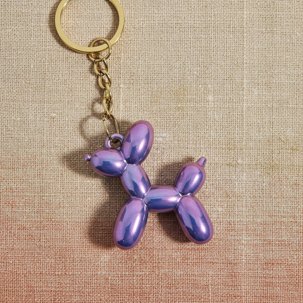 Iridescent purple balloon dog keychain on a light background