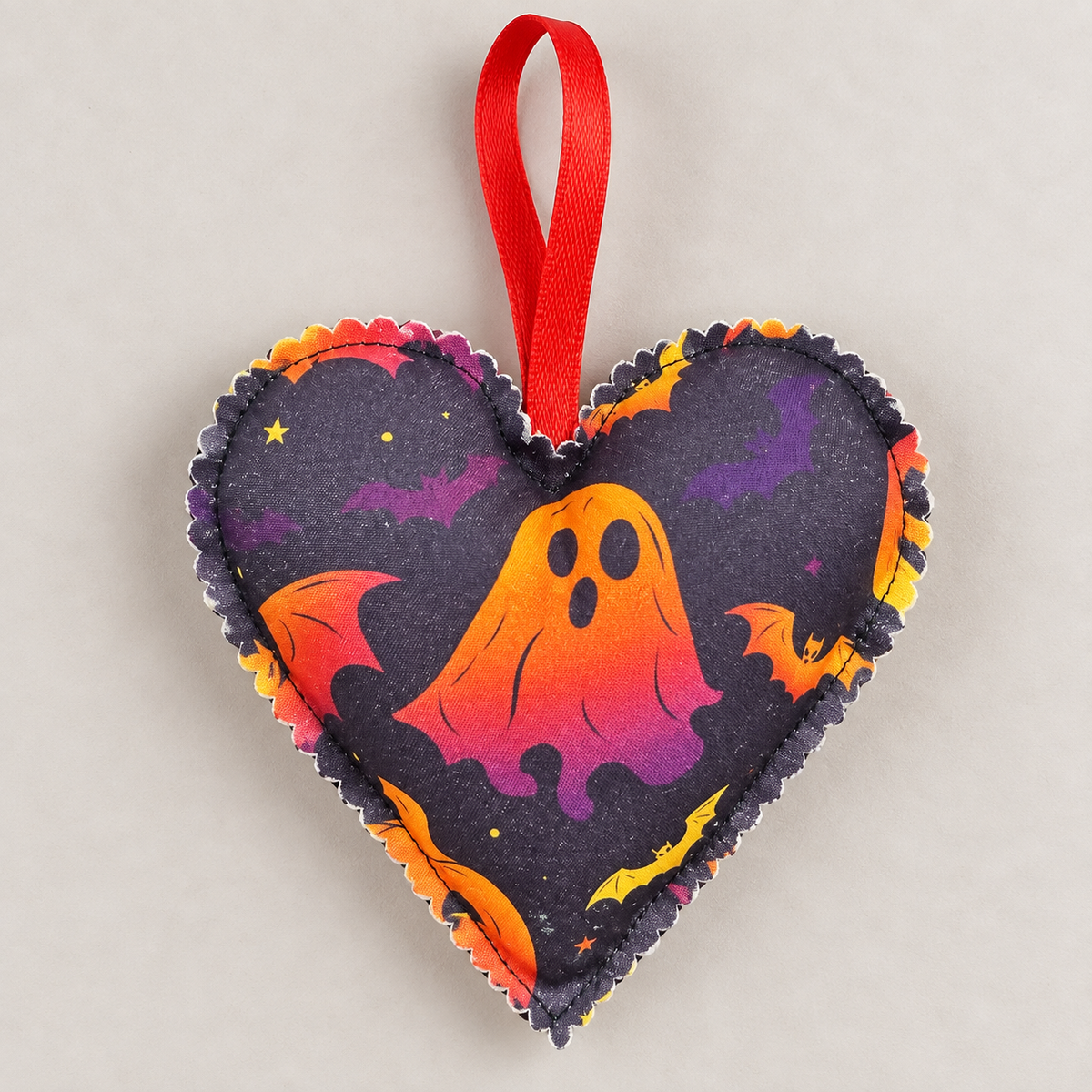 Back of handmade Halloween fabric heart decoration showing colourful Halloween fabric design, scalloped edge and red hanging loop
