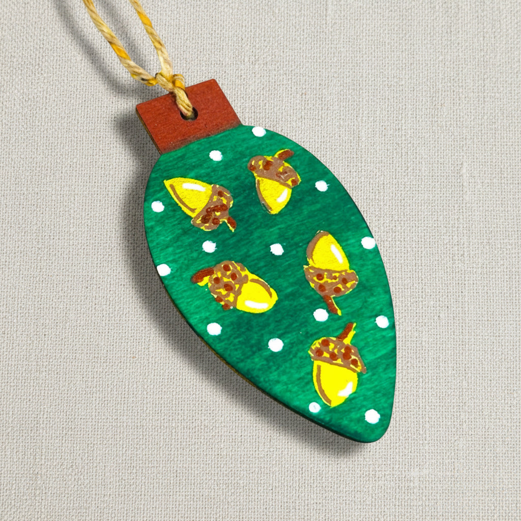 Decorative wooden ornament with hand painted acorn design on a green background