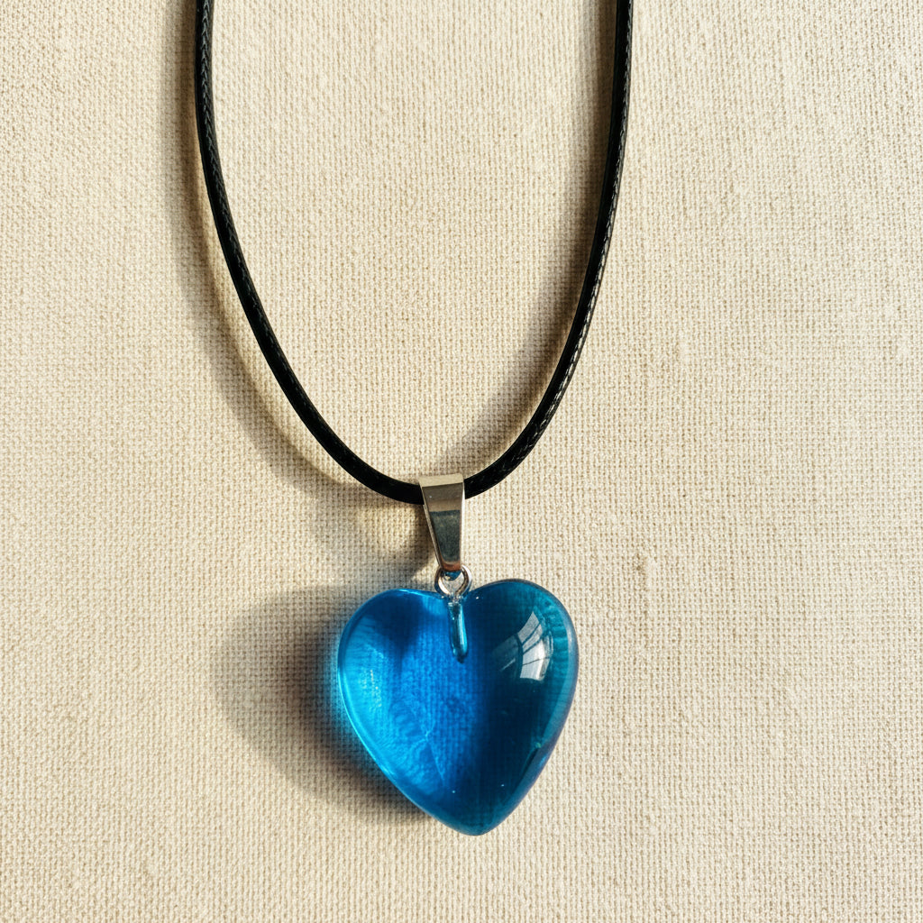 Blue heart-shaped pendant on a black cord against a neutral background