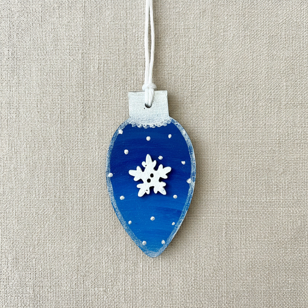Blue Christmas light bulb shaped ornament with a wooden snowflake embellishment 