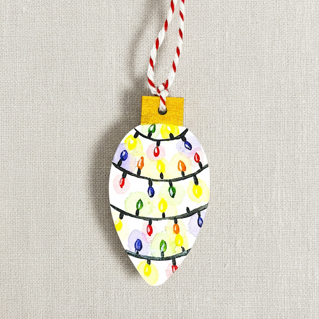 Decorative ornament shaped like a Christmas light bulb hand painted bright colourful lights on a white background