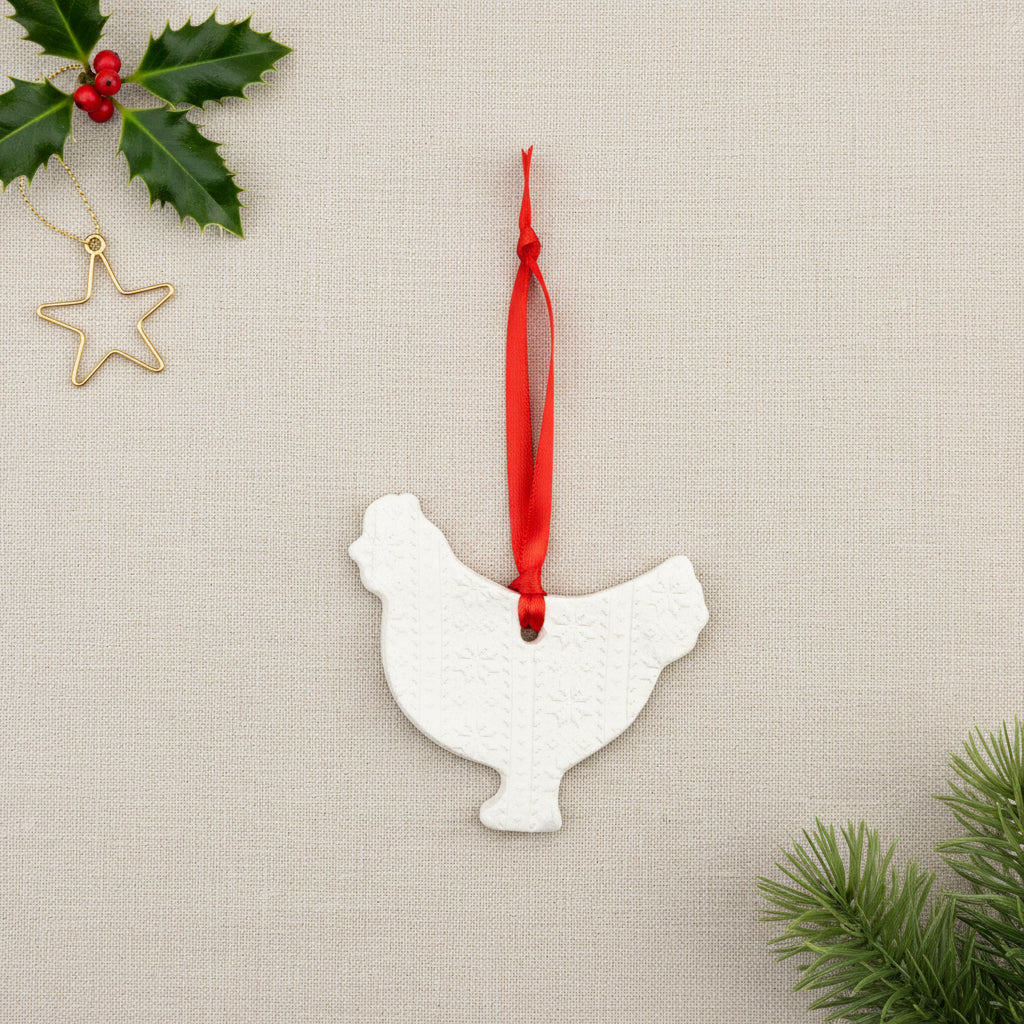 Decorative white clay chicken-shaped ornament with a red ribbon on a white background