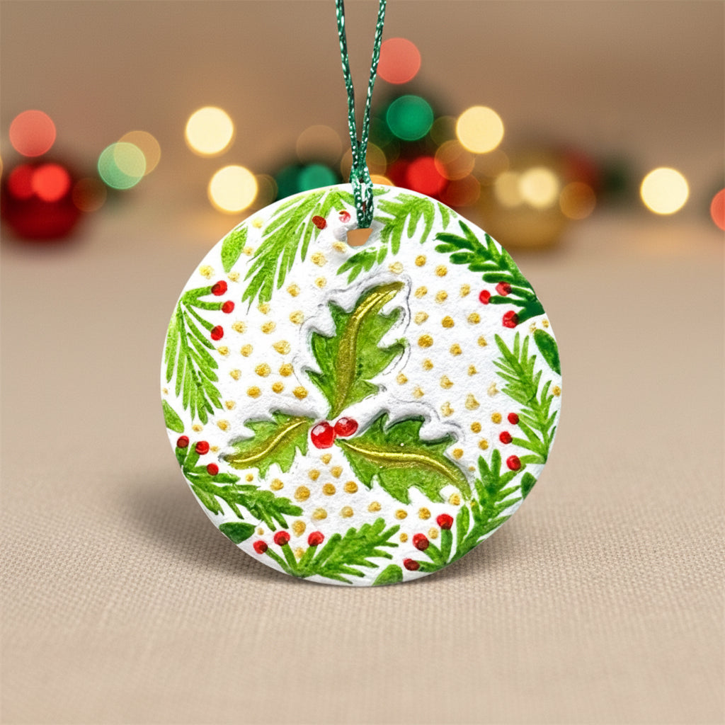 Decorative Christmas ornament with green holly leaves and red berries on a light background 