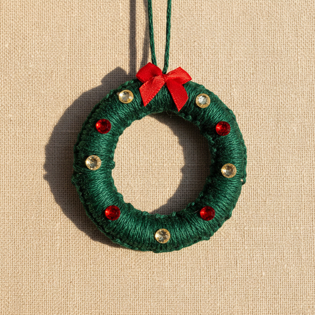 Christmas wreath ornament with red bow and gems on a light background