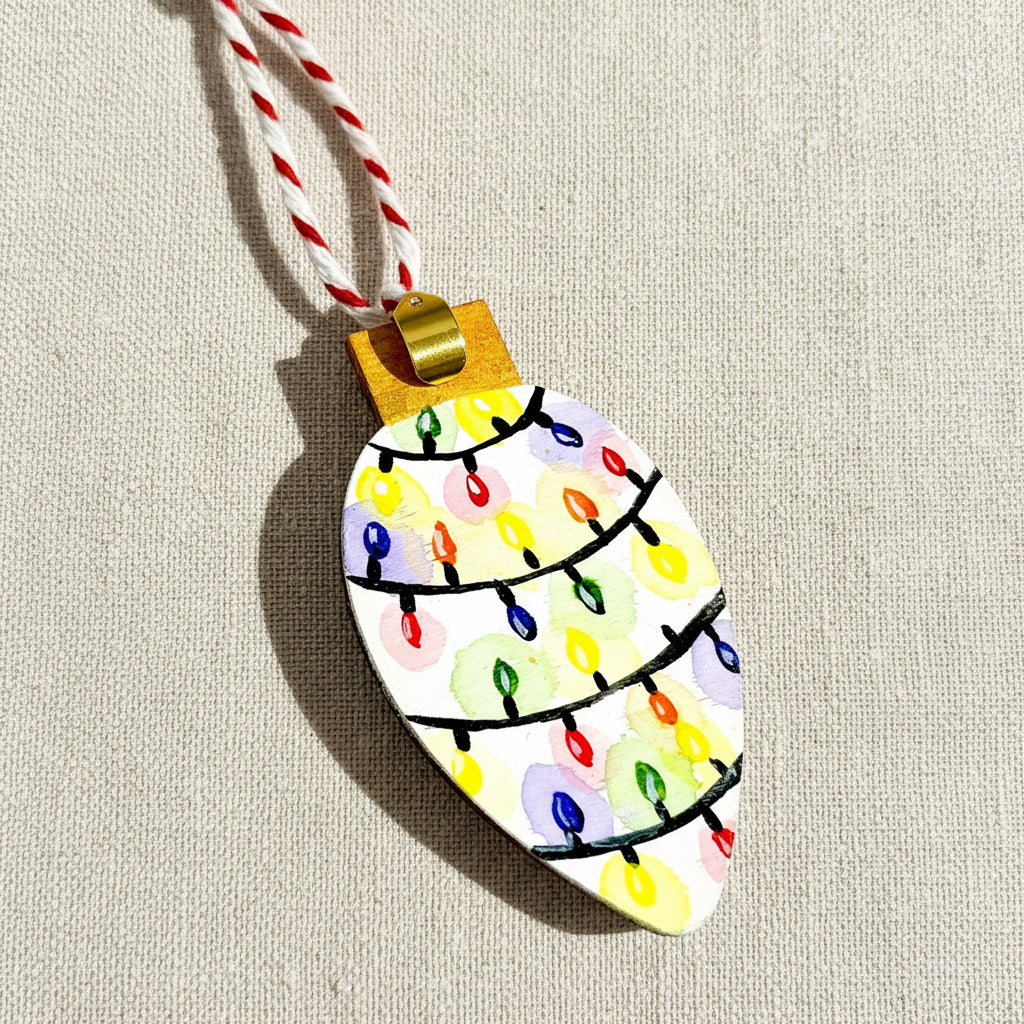 Decorative ornament shaped like a Christmas tree light bulb with colourful hand painted lights on a white background