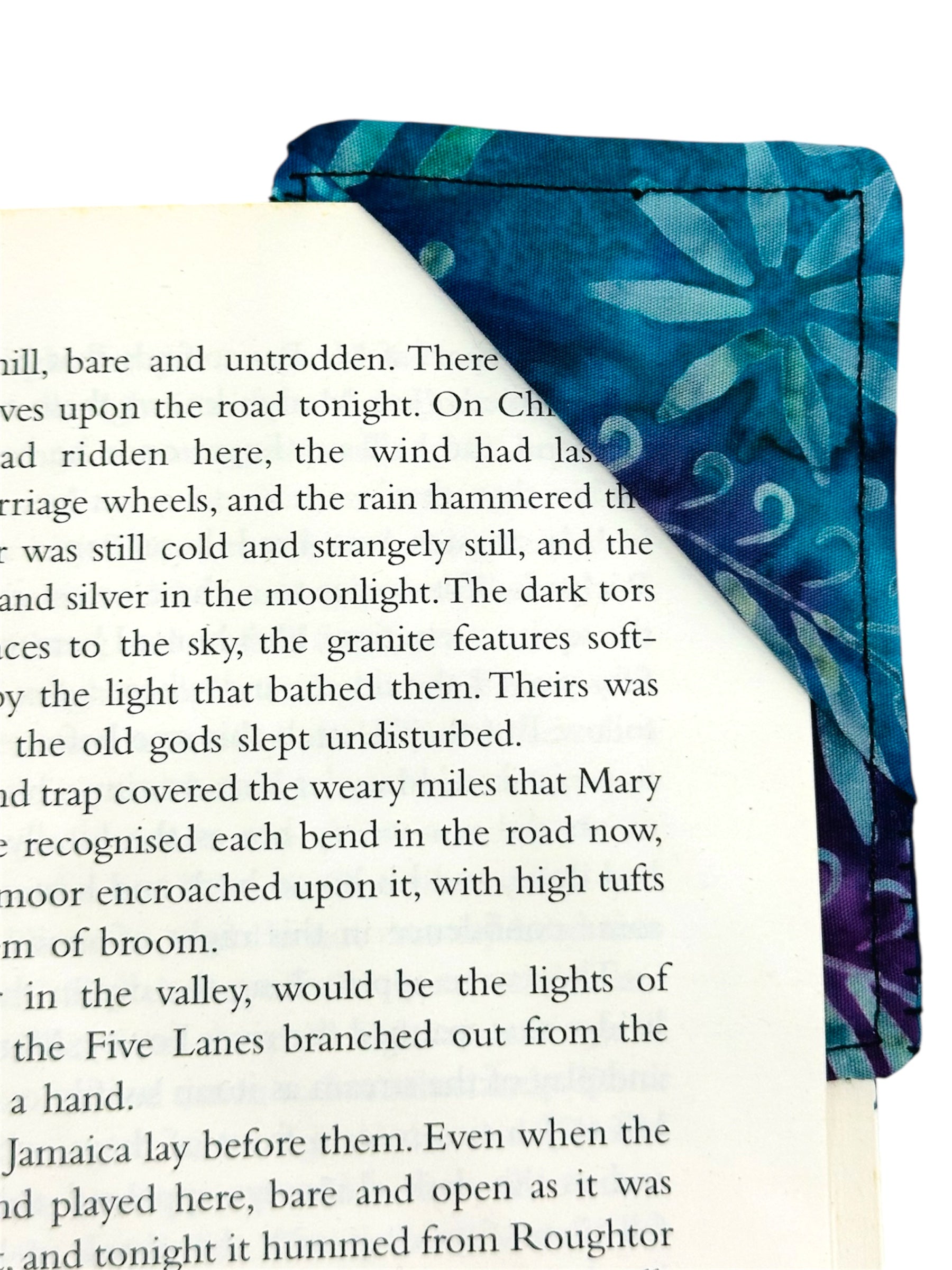 Book with a blue floral bookmark on a page corner 