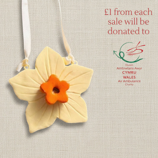 Clay daffodil ornament with ribbon to hang. Yellow flower with an orange centre.