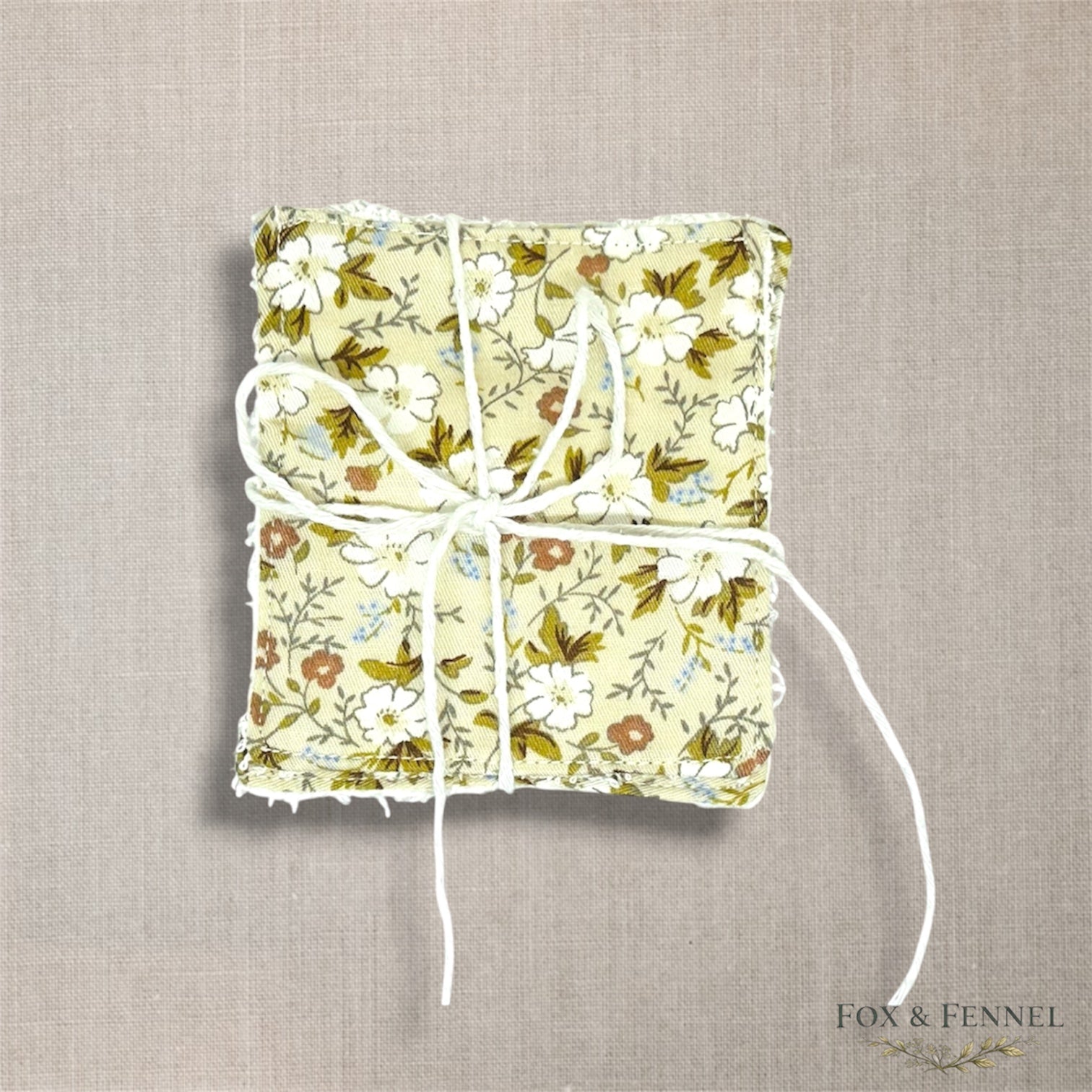 Floral-patterned fabric reusable face wipes retied with string on a textured beige background, with 'Fox & Fennel' branding.
Pack of two 