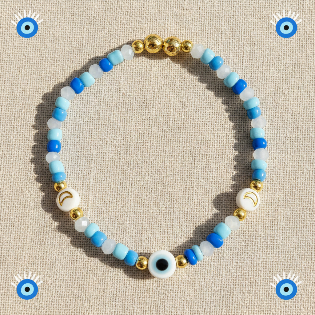 Bracelet with blue, white, and gold beads and evil eye bead on a linen background