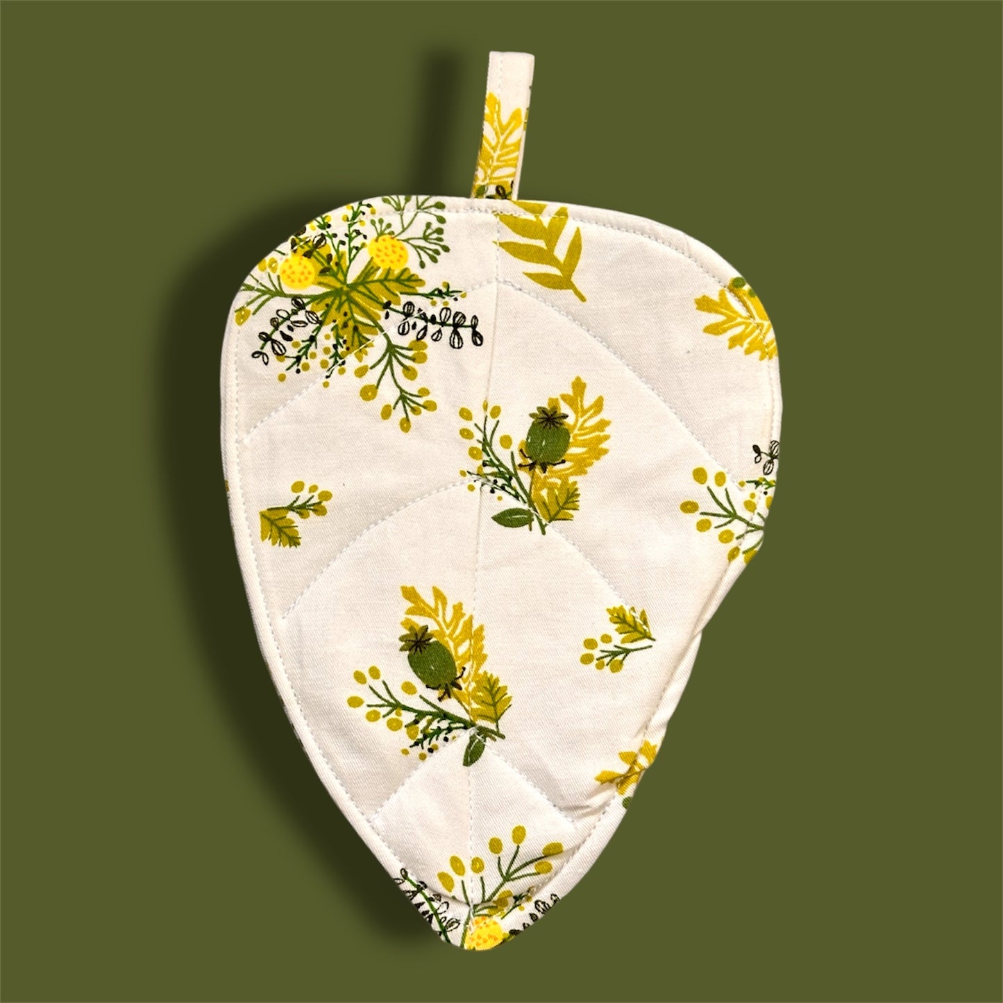 Floral-patterned leaf shaped coaster on a green background