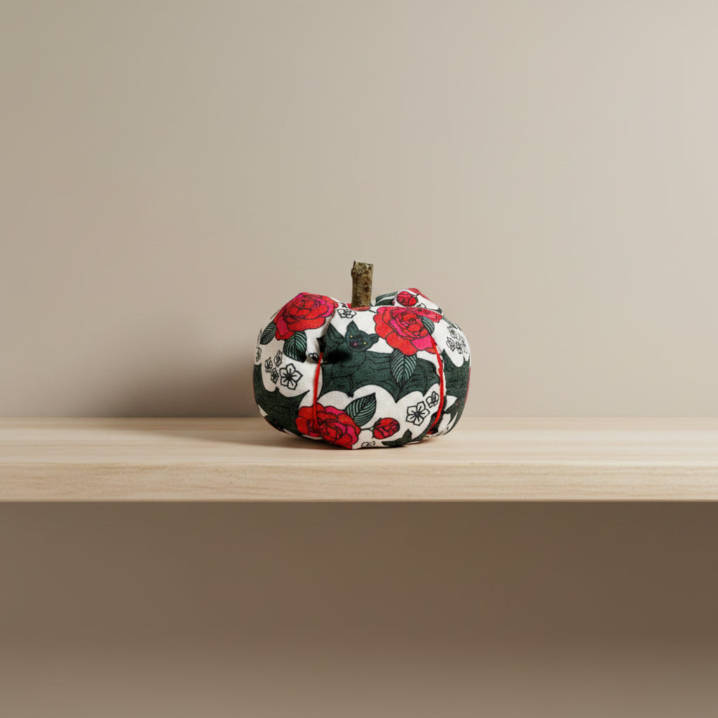 Decorative fabric pumpkin with black bat and red rose pattern on a white background