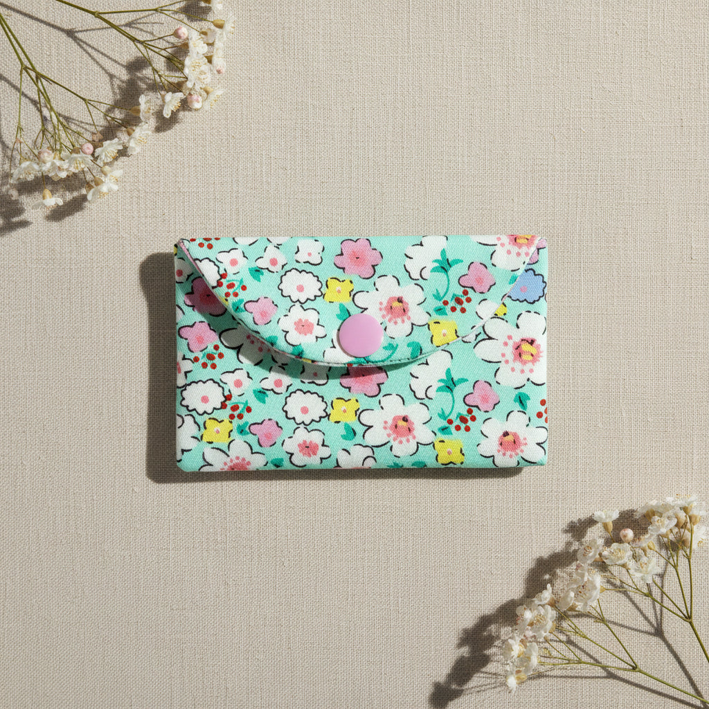 Floral-patterned card wallet with pink snap button fastening 