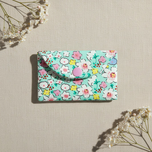 Floral-patterned card wallet with pink snap button fastening 