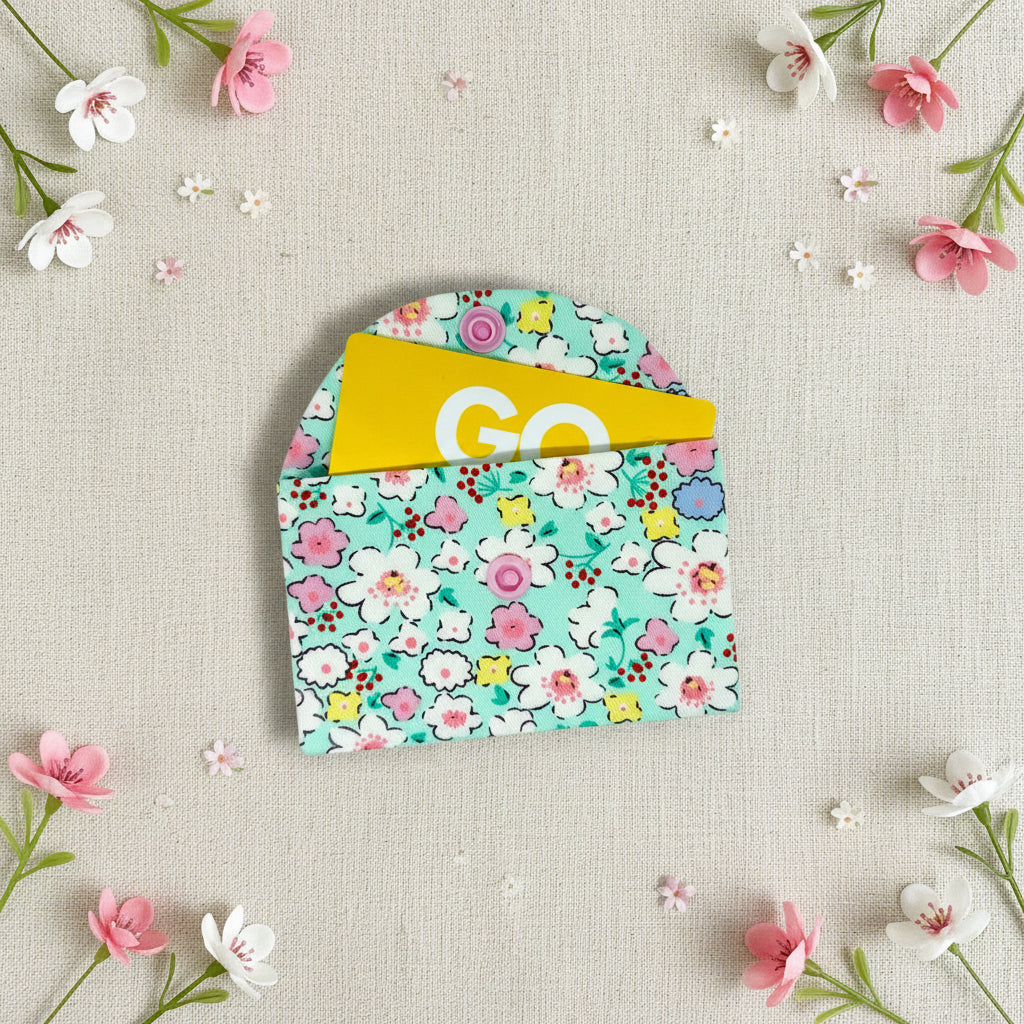 Floral-patterned fabric card wallet with a pink snap button to open and close 