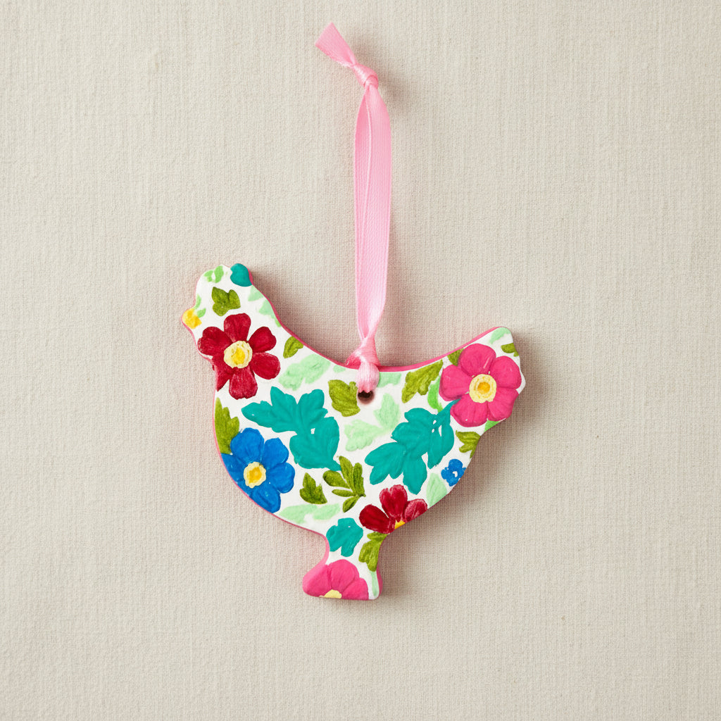 Colourful floral-patterned chicken-shaped ornament with a pink ribbon on a white background