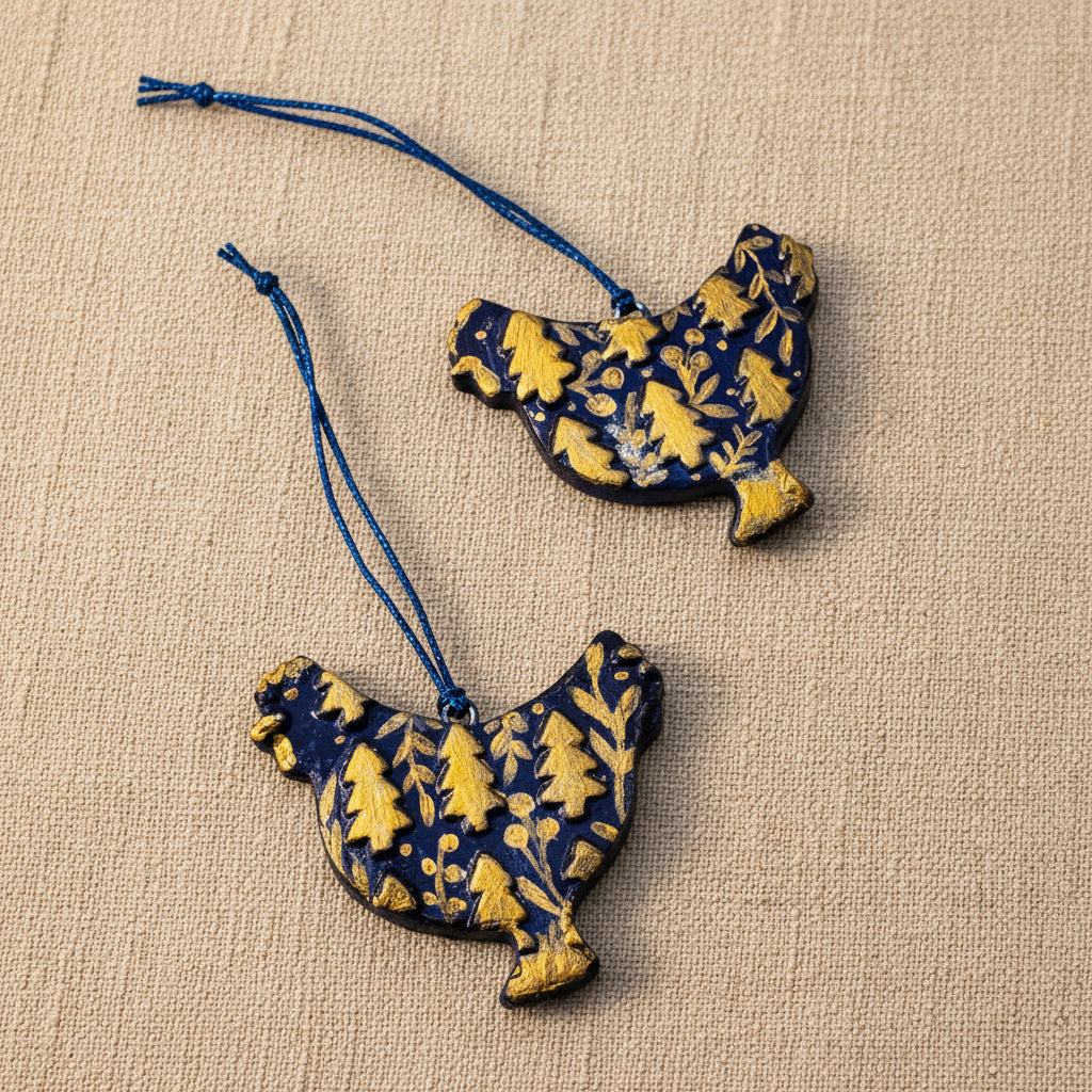 Two clay chicken-shaped ornaments with dark blue and gold patterns