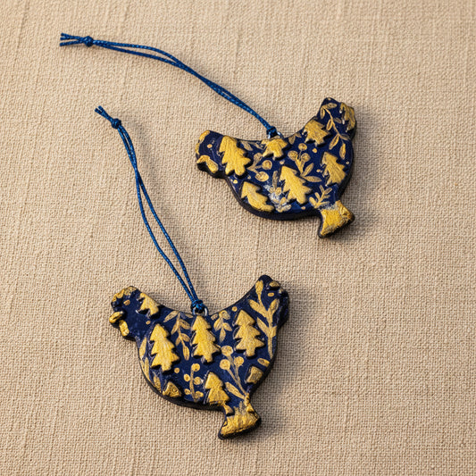 Two clay chicken-shaped ornaments with dark blue and gold patterns
