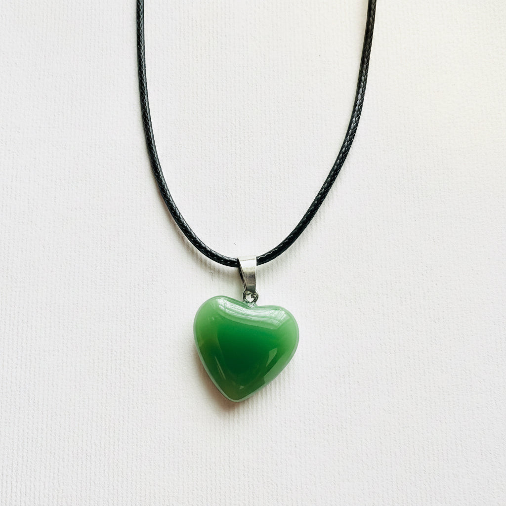 Green heart-shaped pendant on a black cord against a white background