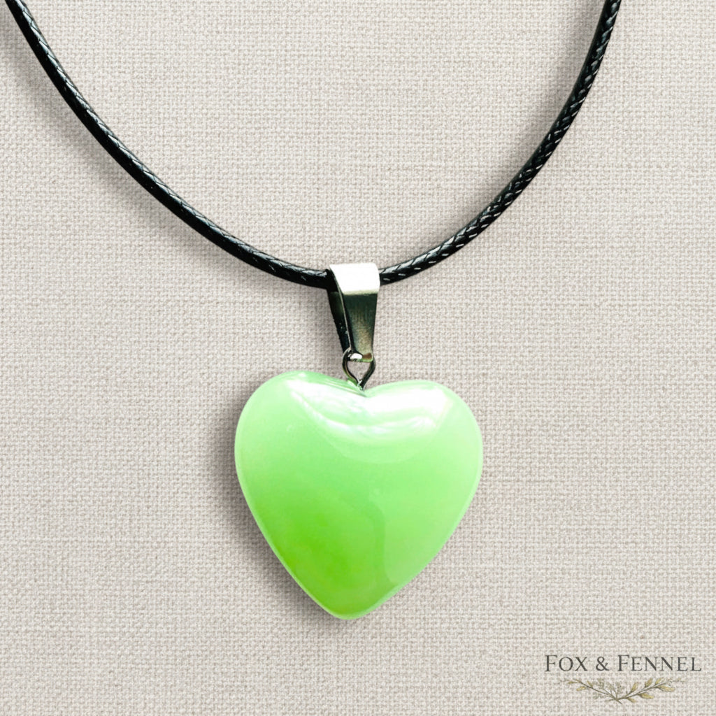 Necklace with a green heart-shaped pendant on a beige background, branded 'FOX & FENNEL'.