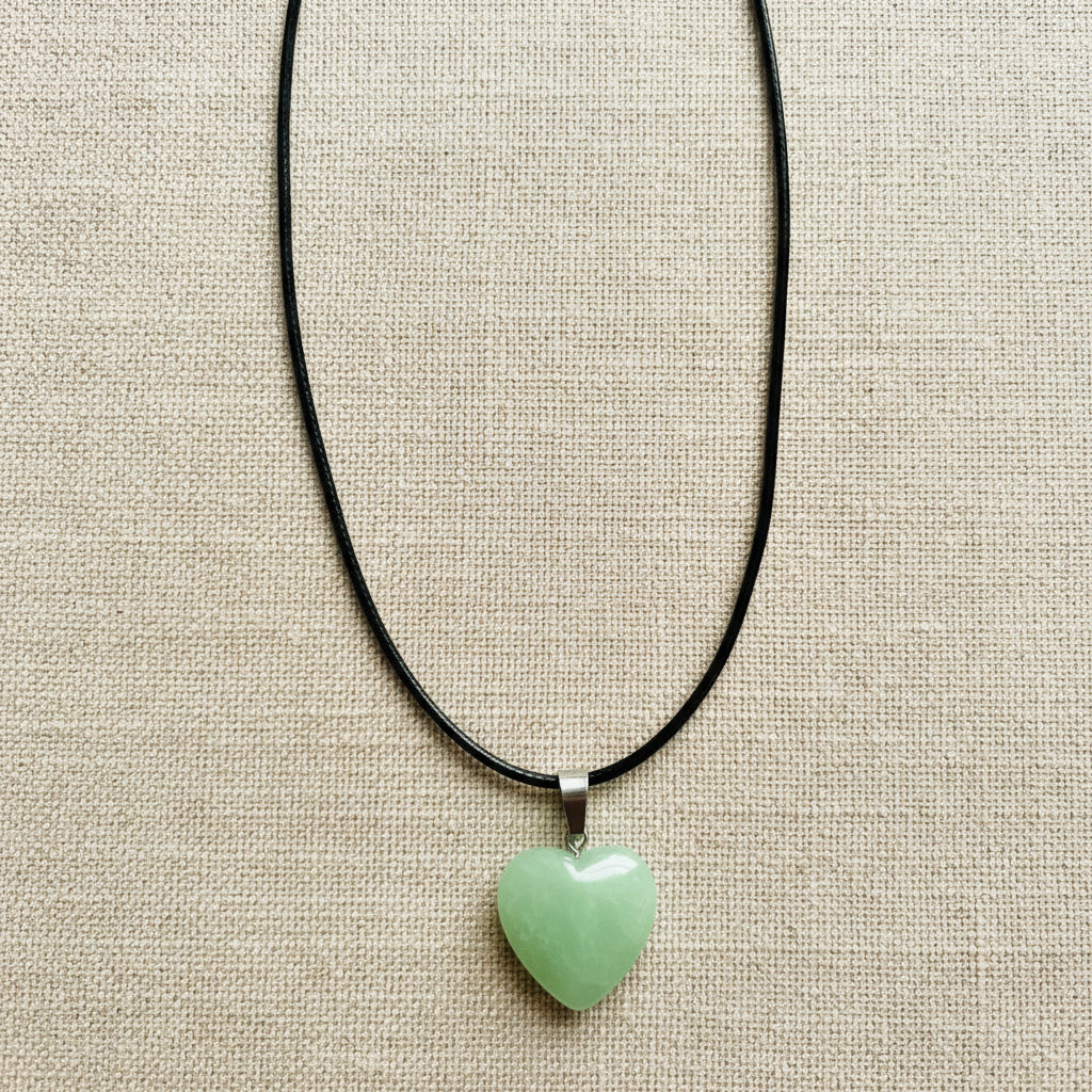 Necklace with a heart-shaped green pendant on a neutral background 