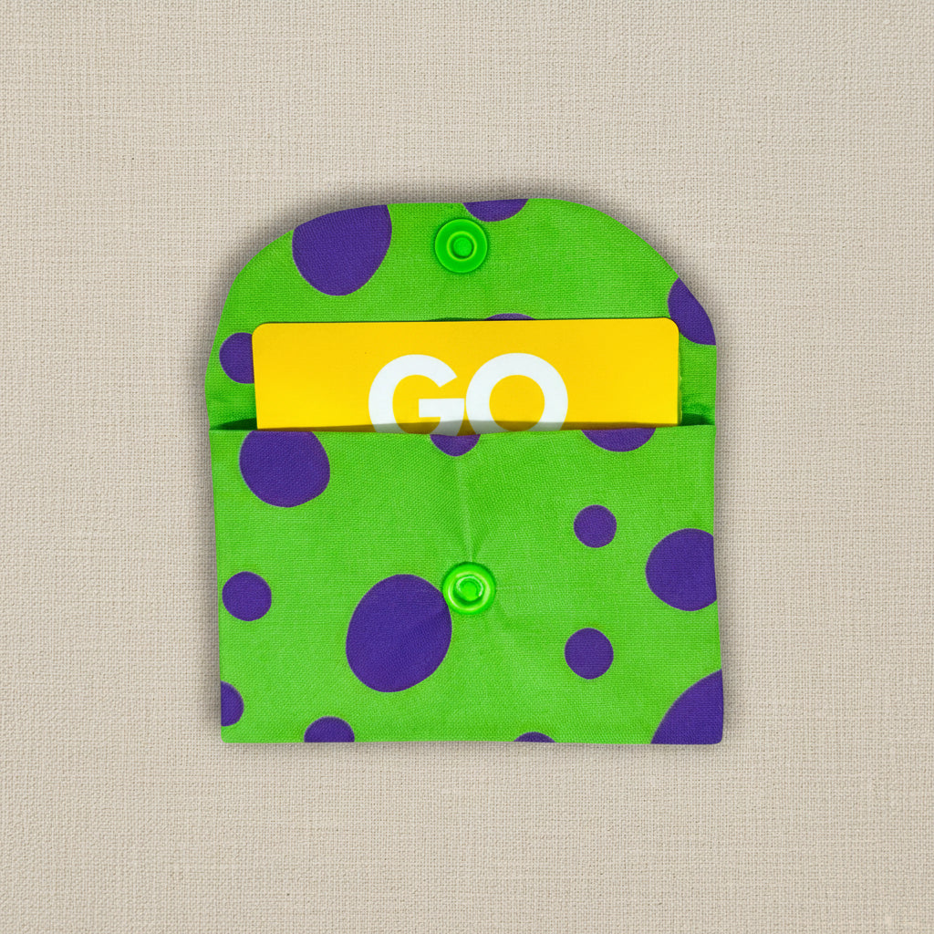 Green card wallet with purple different size dots, wallet is open showing a store card inside 