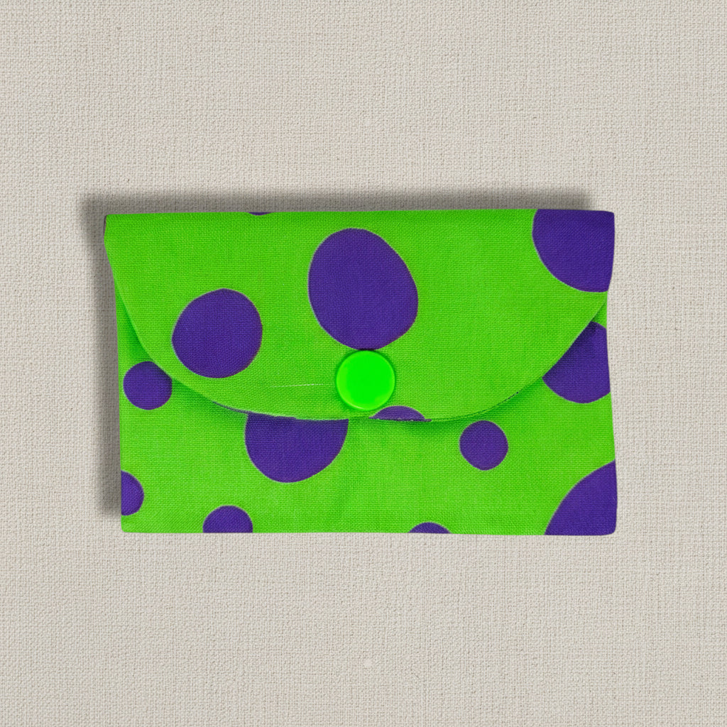 Bright Green envelope style card wallet with purple different sized dots on a linen background