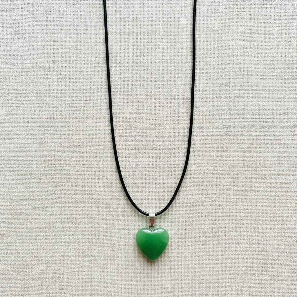 Green heart-shaped pendant on a black cord against a light background