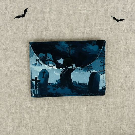 Card wallet with a design of a silhouette of a a tree in a cemetery at night.