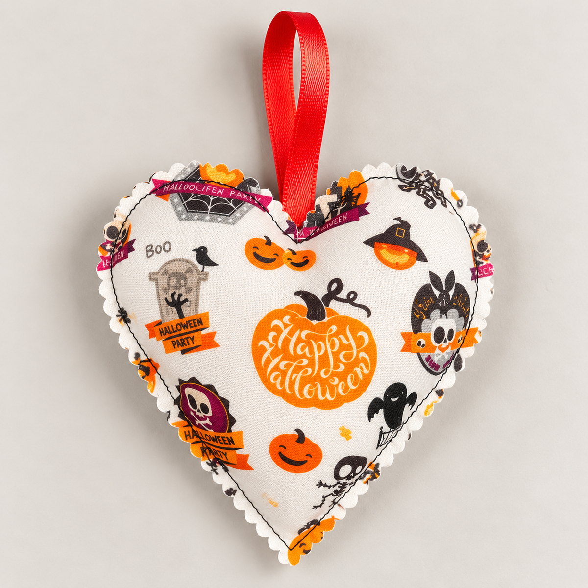 Handmade cream Halloween fabric heart featuring pumpkins, ghosts, bats, skulls and Happy Halloween designs, with a red hanging ribbon