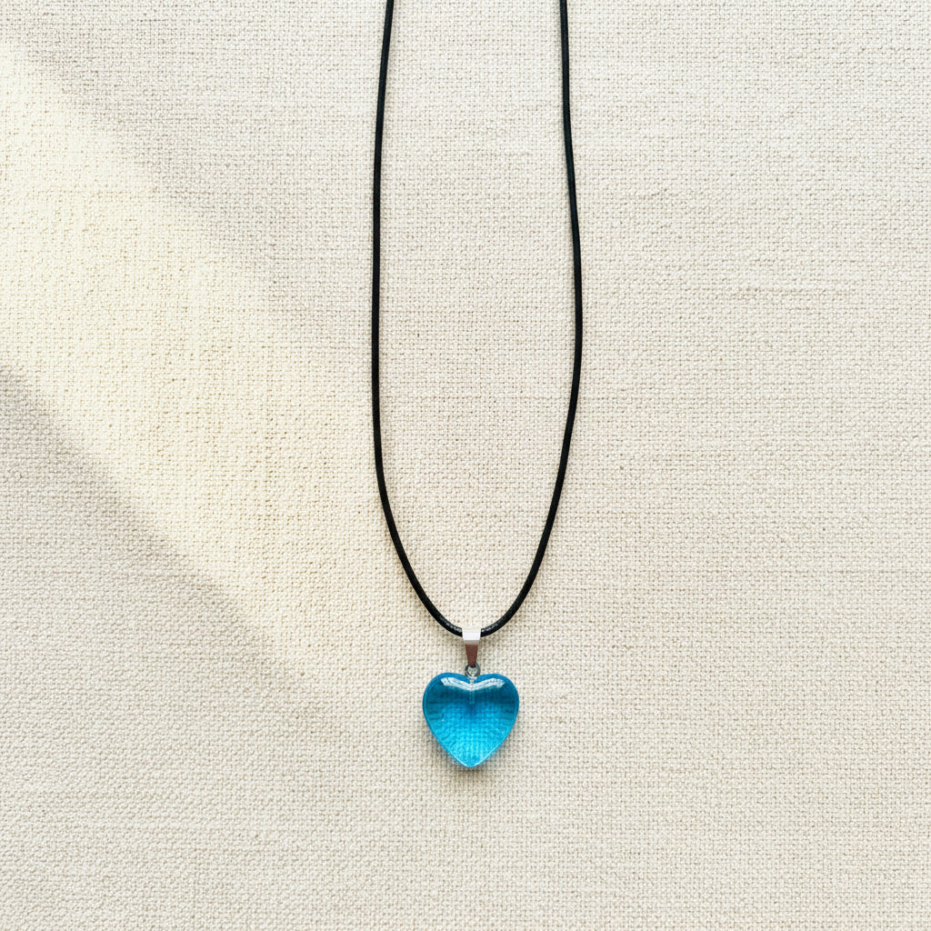 Blue heart-shaped pendant on a black cord against a neutral background