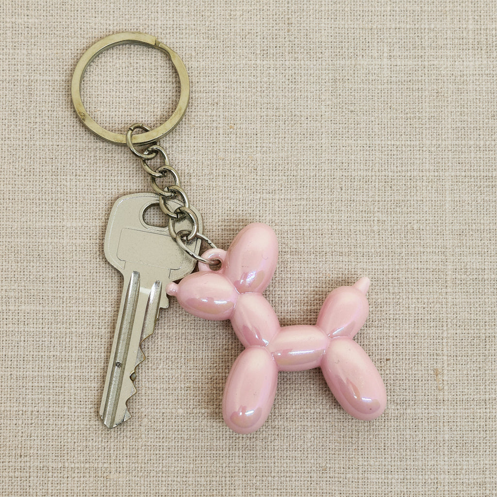 Pink balloon dog keychain on a light background