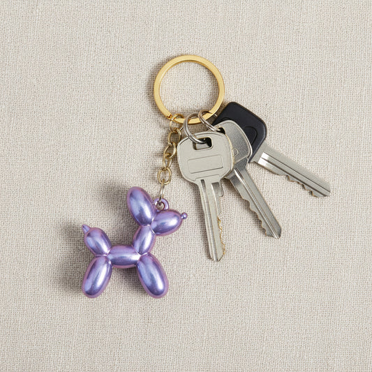 Keychain shaped like a balloon dog with iridescent purple finish on a light background