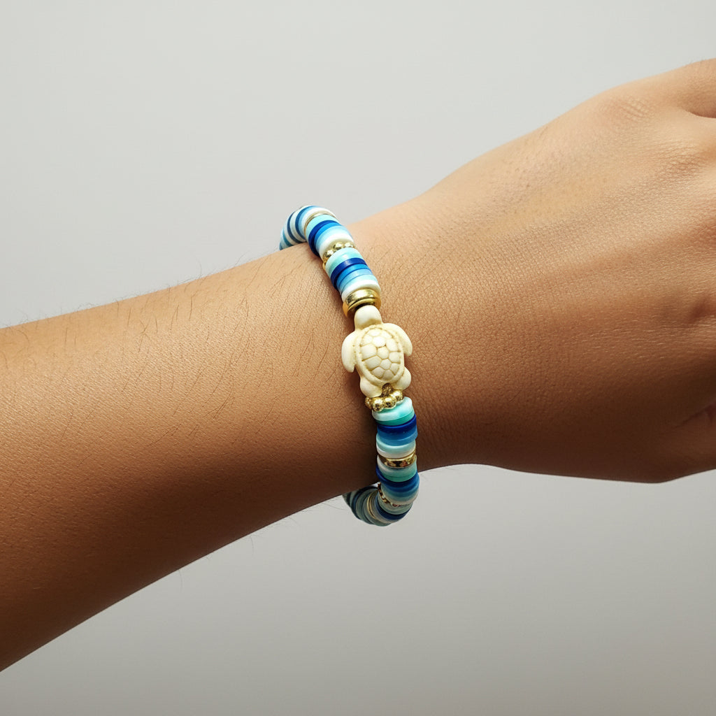 Blue, white, gold beads with a turtle charm on an arm