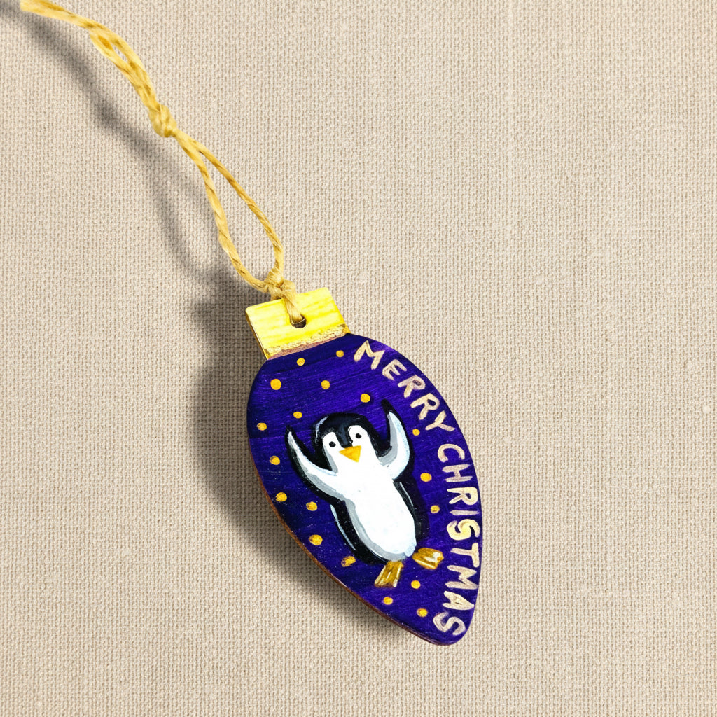 Decorative Christmas ornament with a penguin design and 'Merry Christmas' text on a purple-blue background.