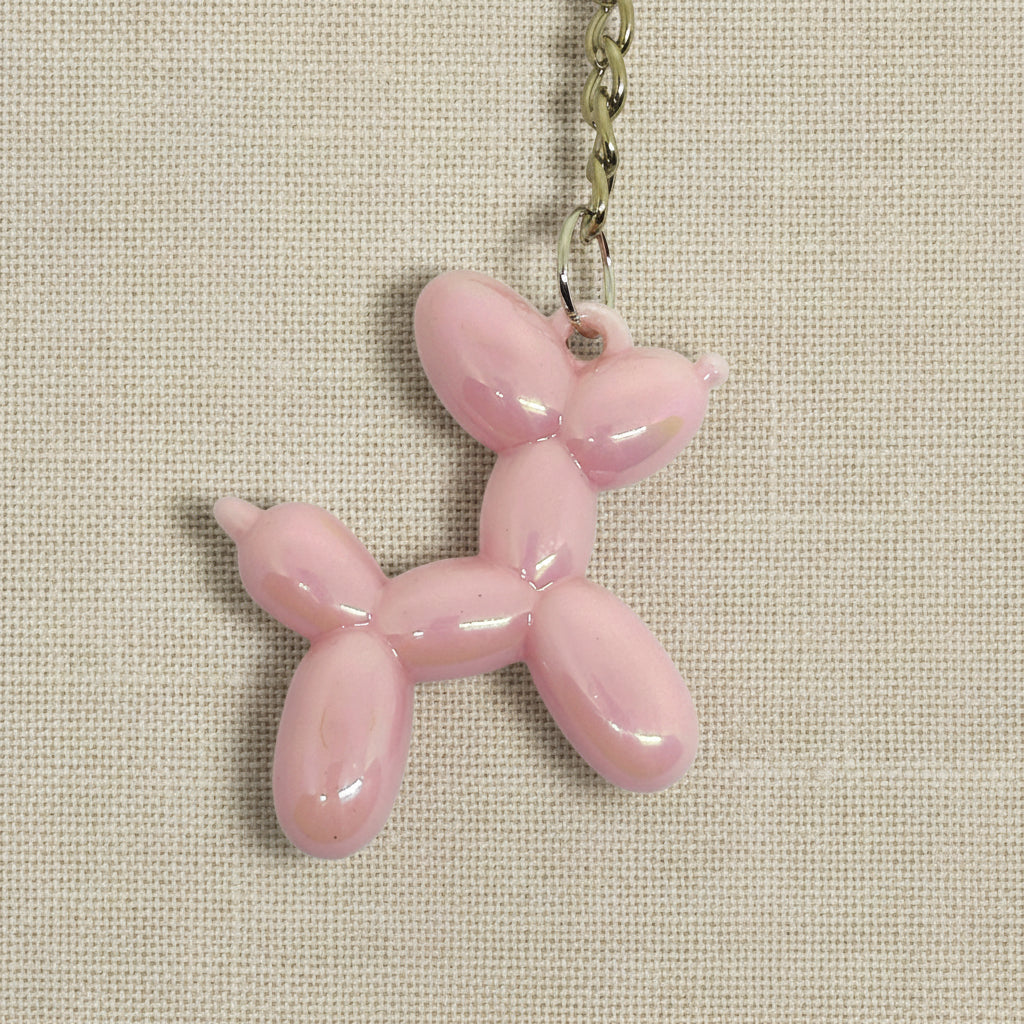 Pink balloon dog keychain on a light background