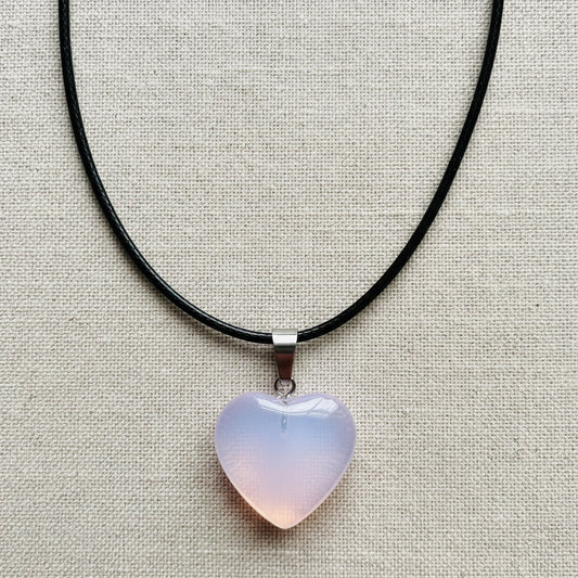 Heart-shaped pendant on a black cord against a neutral background