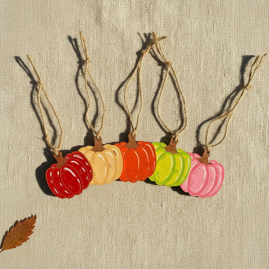 Colourful pumpkin-shaped wooden ornaments on strings against a linen background