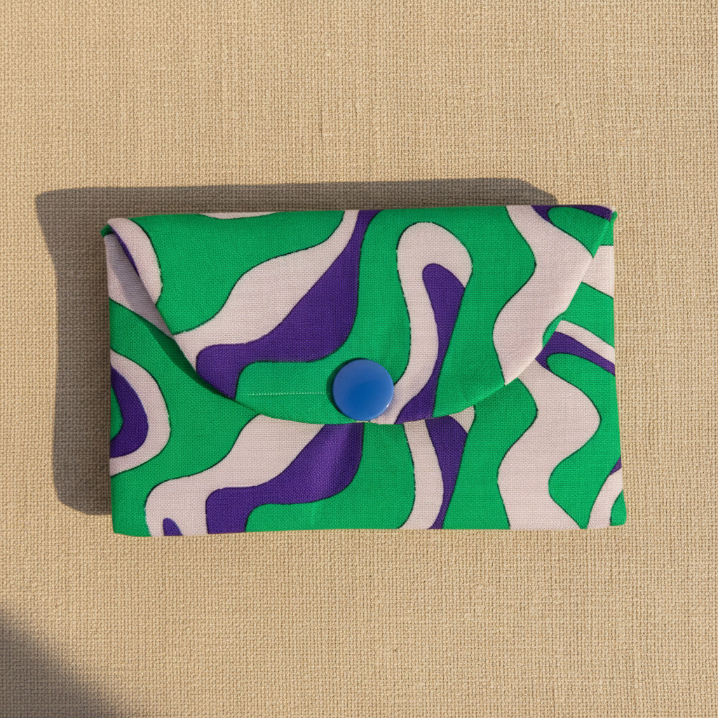Green,purple and pink abstract pattern fabric card wallet on a neutral background