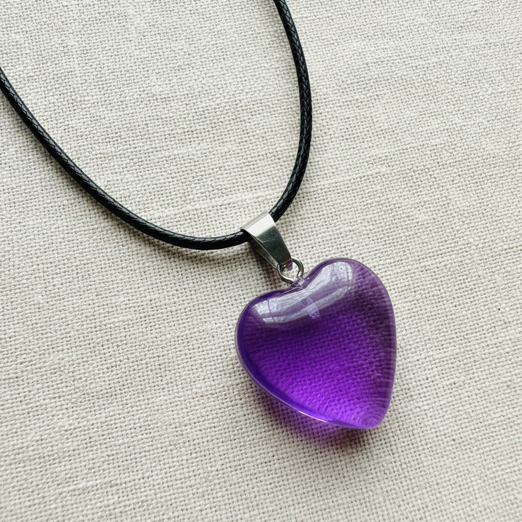 Purple heart-shaped pendant on a black cord against a neutral background