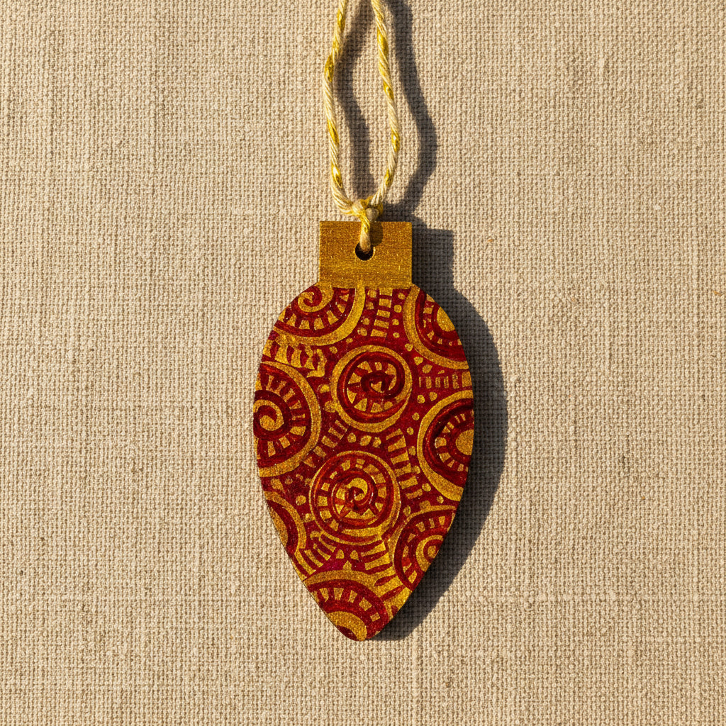 Decorative wooden Christmas tree decoration with gold and red pattern on a neutral background