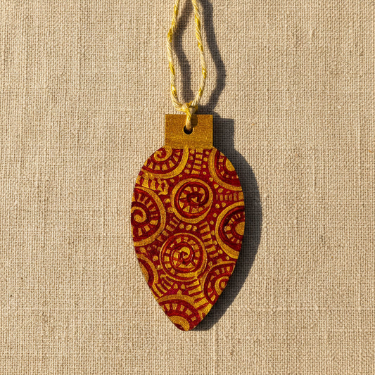 Decorative wooden Christmas tree decoration with gold and red pattern on a neutral background