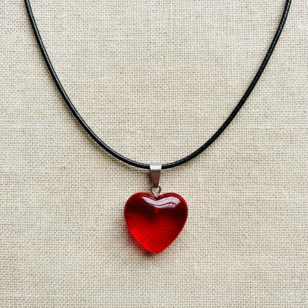 Red heart-shaped pendant on a black cord against a neutral background