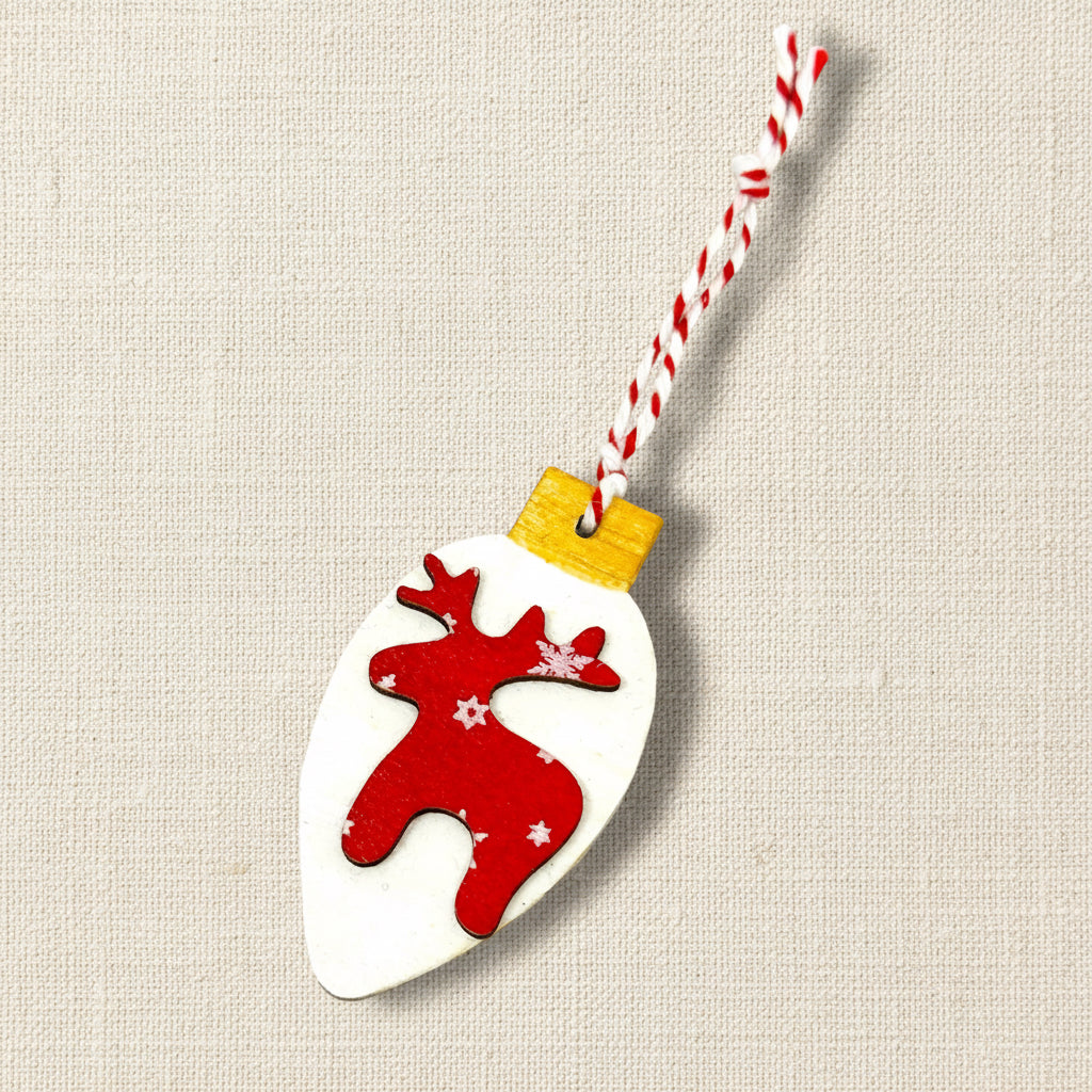 Red reindeer-shaped wooden ornament on a Christmas light shaped wooden flat bauble on a white background