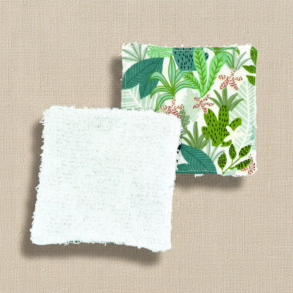Two reusable fabric face wipes, one shown botanical fabric, one showing white flannel (the underside) square shape 