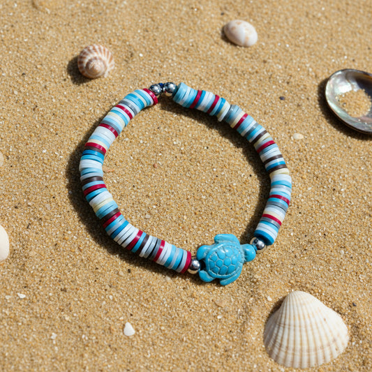 Colourful beaded bracelet with a blue turtle charm on a sandy background