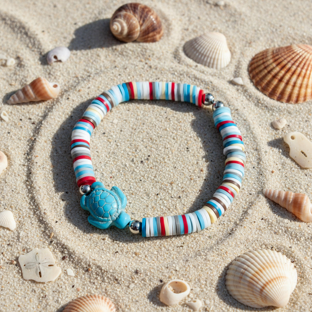 Striped bracelet with a turtle charm on a sandy background