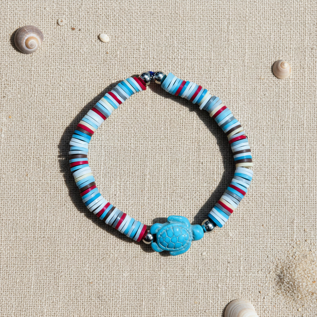 Striped bracelet with a blue turtle charm on a white background