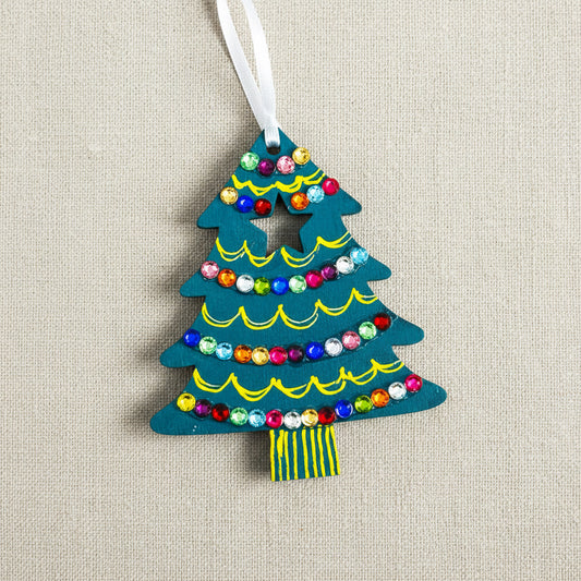 Decorative wooden Christmas tree ornament with colourful gems on a teal background